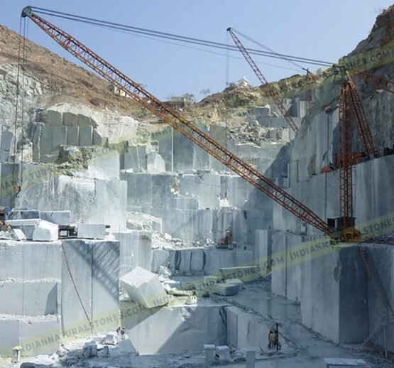 Natural stone quarrying and block extraction operations by Indian Natural Stones, showcasing large-scale stone mining and crane handling at the quarry site