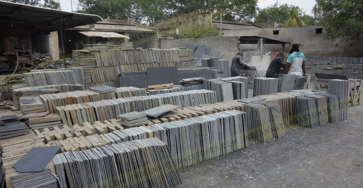Stacked natural stone slabs and tiles at Indian Natural Stones factory yard for processing and export