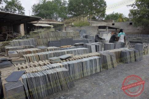Stacked natural stone slabs and tiles at Indian Natural Stones factory yard for processing and export {{brizy_dc_image_alt imageSrc=