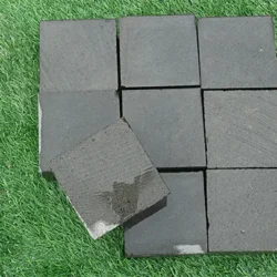 Basalt saw cut cobblestone pavers in dark grey finish arranged in a grid for outdoor paving by Indian Natural Stones.