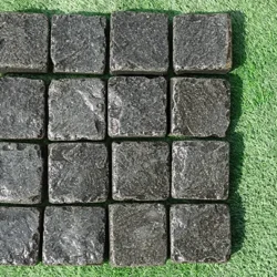 Black basalt cobblestone pavers in square shape with natural textured finish arranged in a grid by Indian Natural Stones.