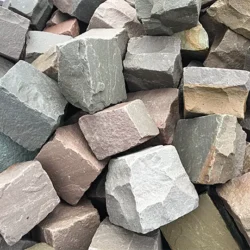 Natural multi-color sandstone cobblestones with rough hand-cut texture for outdoor paving by Indian Natural Stones.
