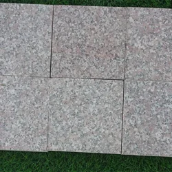 Pink granite flamed cobblestone pavers arranged in a neat layout for outdoor paving by Indian Natural Stones.