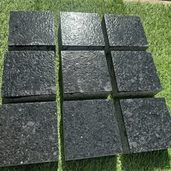 Black granite cobblestone pavers with lapato finish arranged in a grid pattern for outdoor use by Indian Natural Stones.