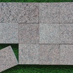 Flamed red granite cobblestone pavers arranged in a grid pattern for outdoor flooring by Indian Natural Stones.