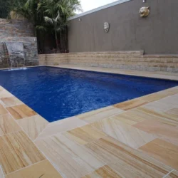 Teak sandstone natural stone paving by Indian Natural Stones installed around swimming pool patio for elegant outdoor landscape design