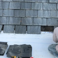 Worker drilling hole in natural slate roofing tile for fixing by Indian Natural Stones