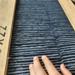 Close-up of hand touching black slate roofing tiles showcasing natural texture by Indian Natural Stones